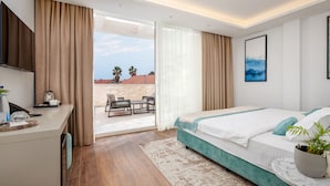 Una habitación de hotel moderna con cama, escritorio, televisor y balcón con mobiliario exterior.