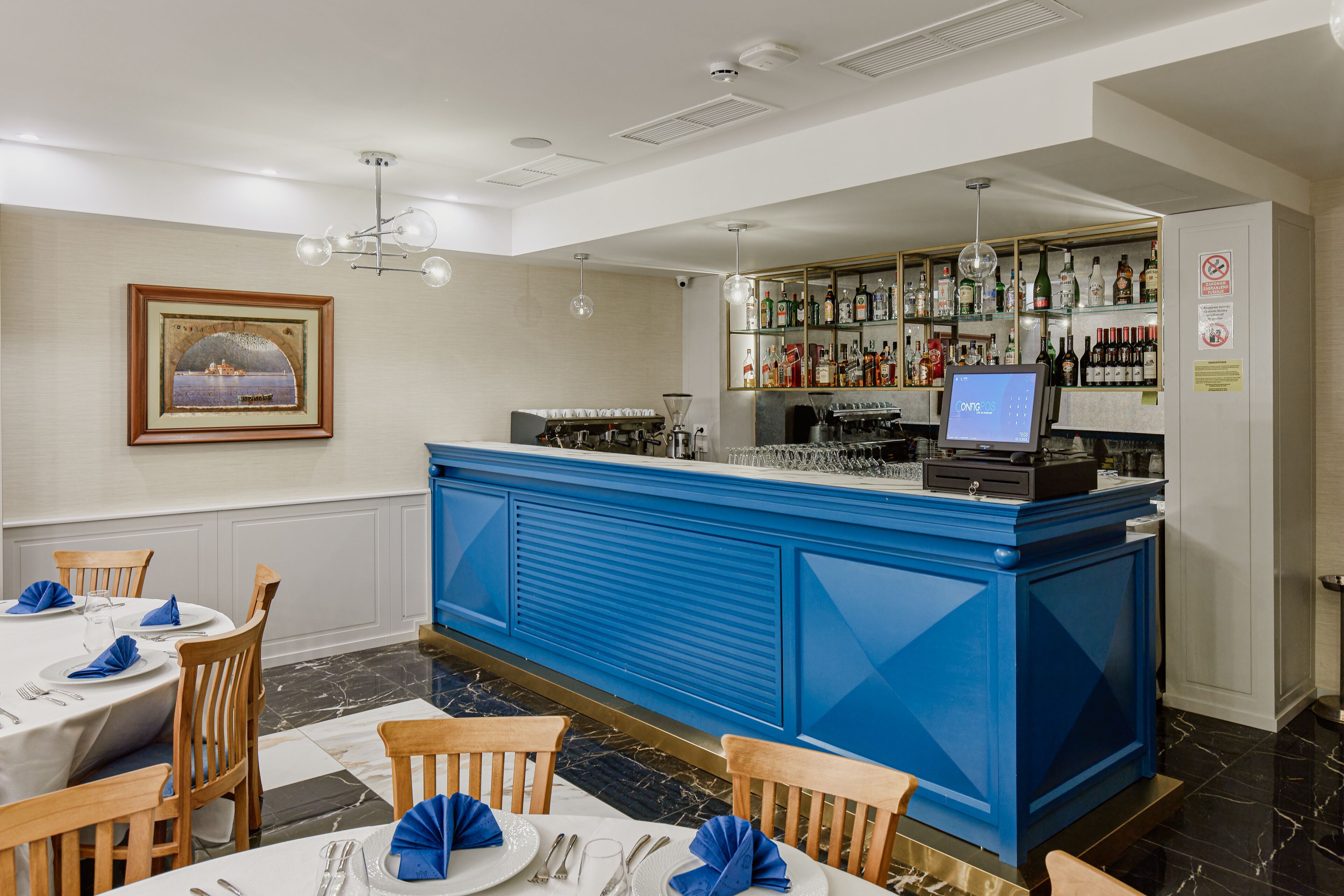 A restaurant with a blue bar area, white tables, and chairs.