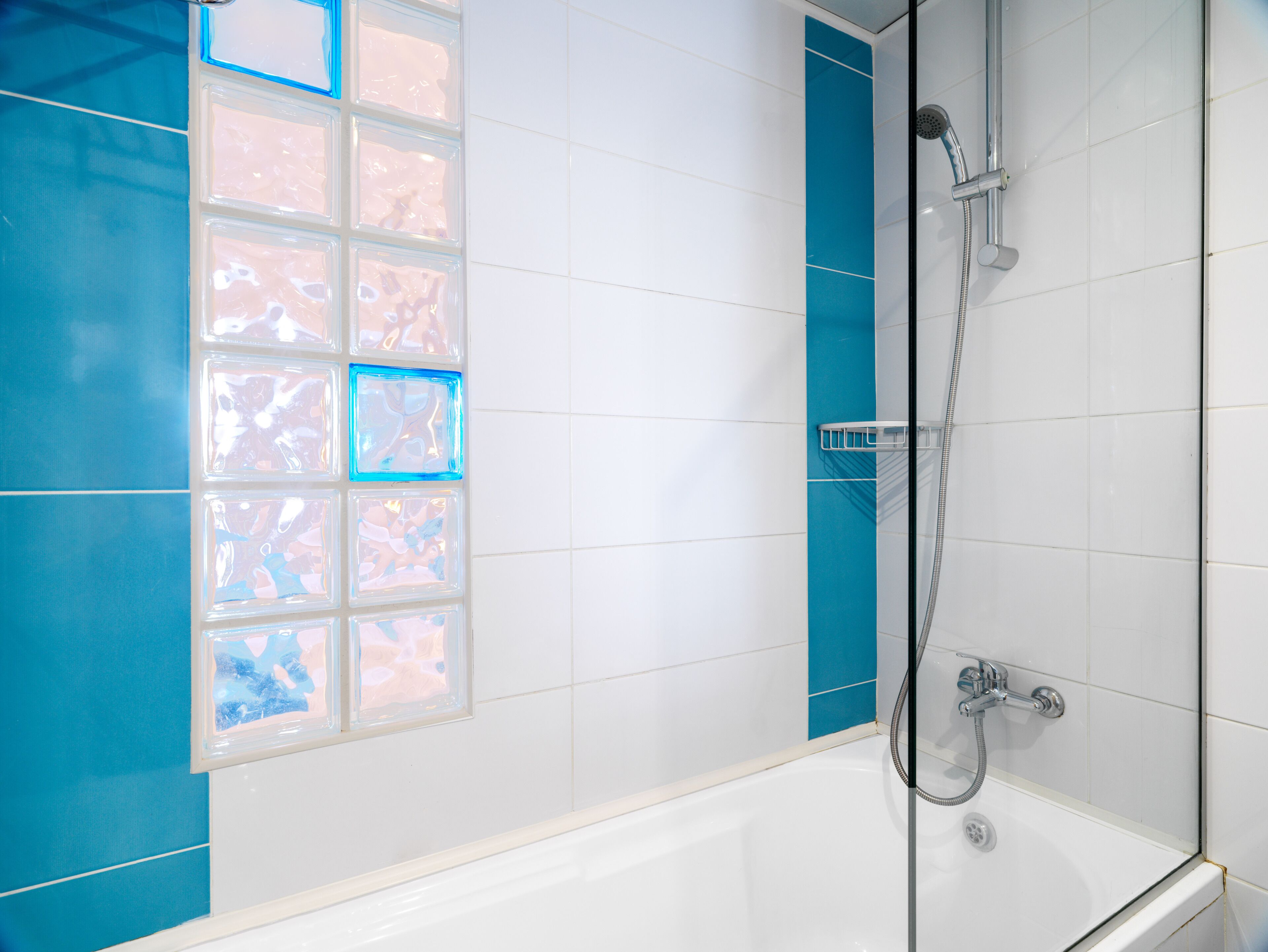 A bathroom with a bathtub, a shower, and a window with frosted glass panels.