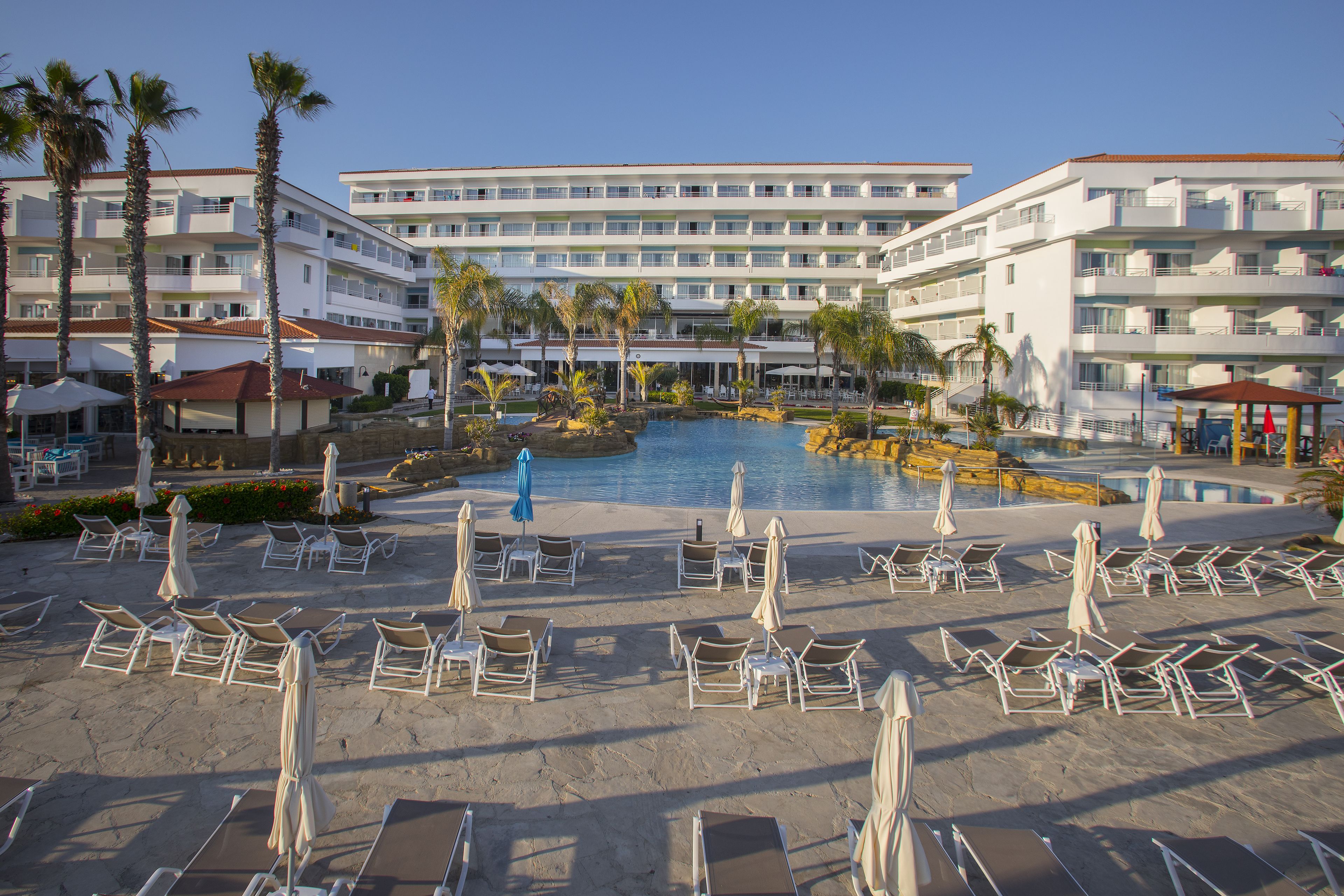 A hotel with a pool area, multiple floors, and outdoor seating with umbrellas.