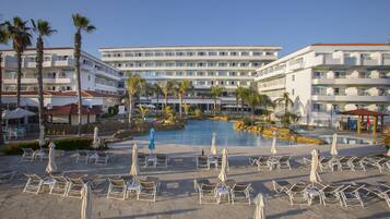 A hotel with a pool area, multiple floors, and outdoor seating with umbrellas.