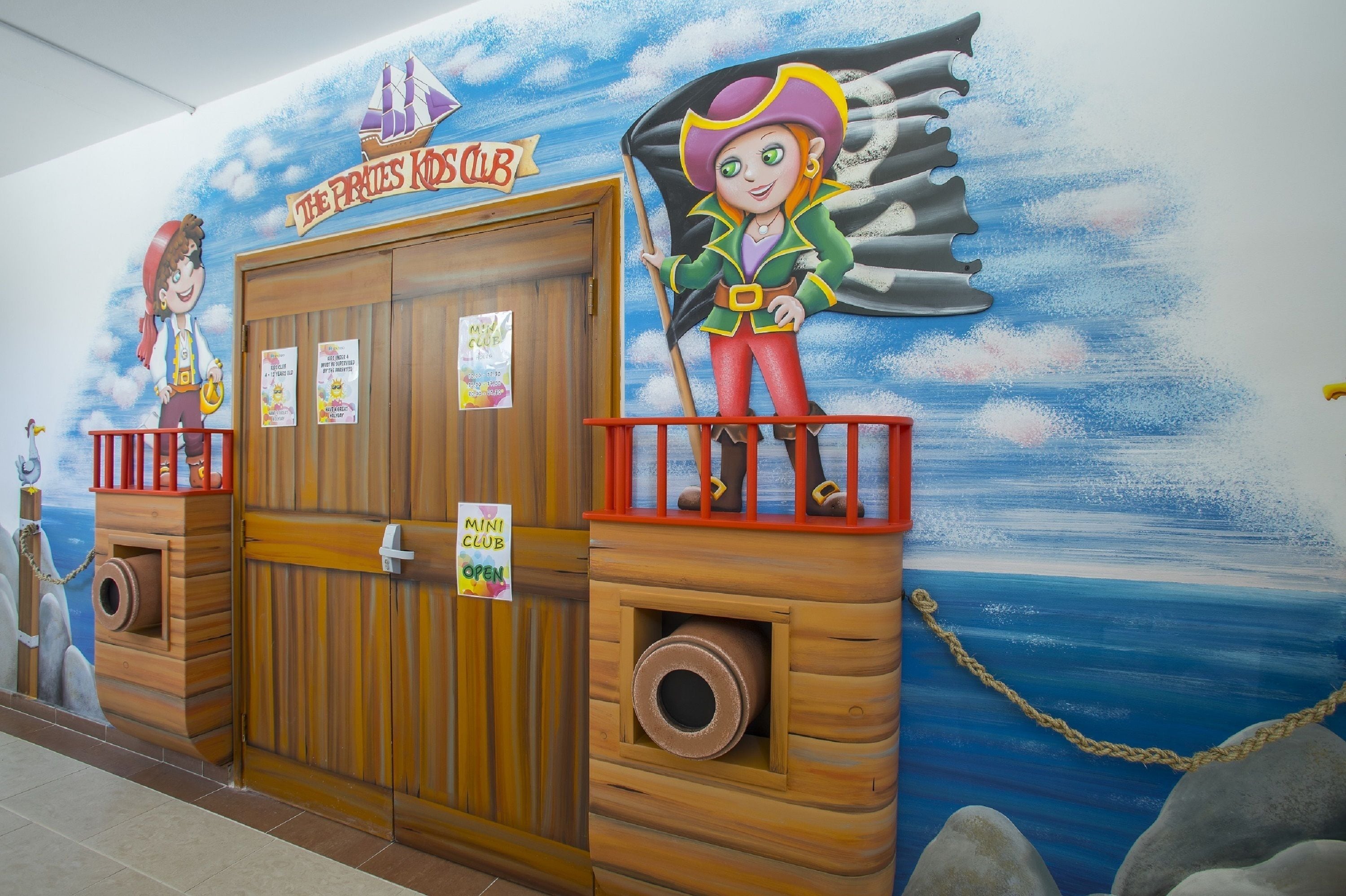 A wooden door with a sign indicating 'The Pirates Club' and 'Mini Club Open'.