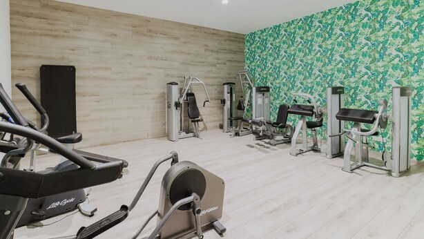 A gym with cardio machines, weight machines, and a patterned wall. - Tasia Maris Seasons (Ayia Napa)