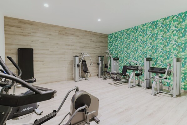A gym with cardio machines, weight machines, and a patterned wall. - Tasia Maris Seasons (Ayia Napa)