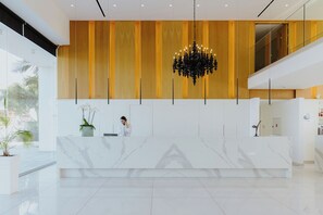 A modern reception area with a marble counter, a large chandelier, and wooden paneling on the wall. - Tasia Maris Seasons (Ayia Napa)