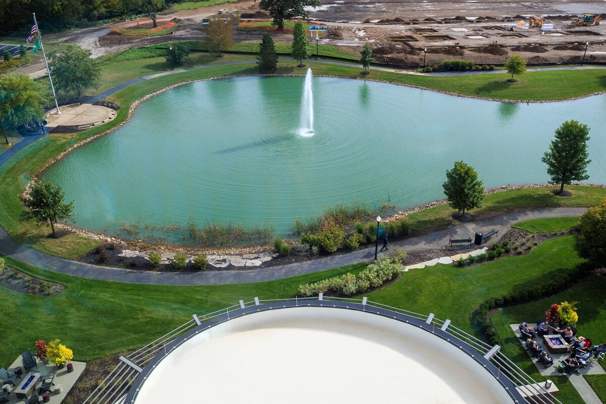 A large pond with a fountain, surrounded by a walking path and seating areas.
