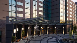 A hotel entrance with a covered walkway, a sign reading "NAISSANCE HOTEL," and a landscaped area with planters and benches. - Renaissance Columbus Westerville-Polaris Hotel (Westerville)