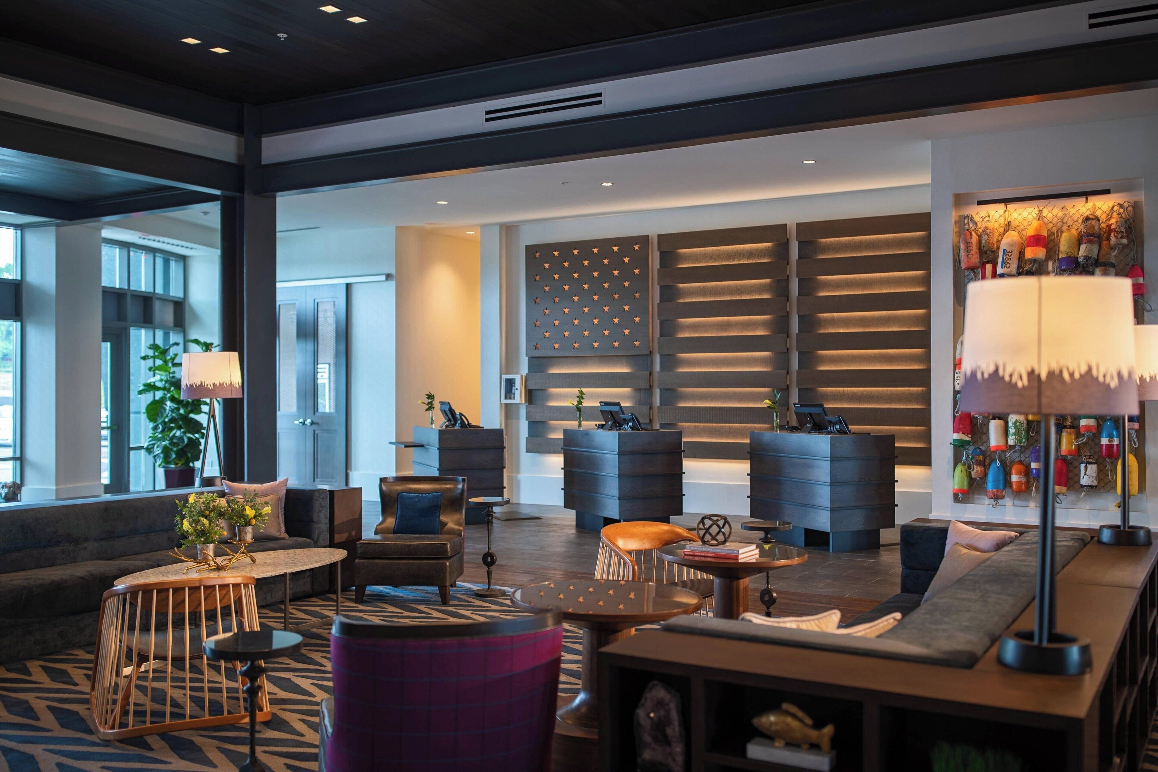 A modern hotel lobby with a seating area, a reception desk, and a wall with decorative elements.