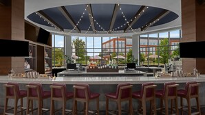 A modern bar area with a curved ceiling, large windows, and bar stools. - Renaissance Columbus Westerville-Polaris Hotel (Westerville)