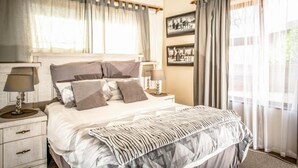 A neatly arranged bedroom with a bed, bedside tables, and curtains. - Seaview Luxury (Jeffreys Bay)