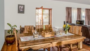 A wooden dining table with a placemat, a potted plant, and a vase with flowers. - Seaview Luxury (Jeffreys Bay)