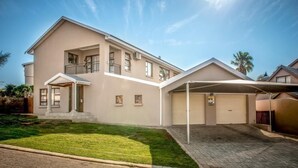 A two-story residential building with a covered driveway and a front lawn. - Seaview Luxury (Jeffreys Bay)