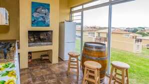 A kitchen with a large window, a refrigerator, a wooden barrel, and a painting of a dolphin. - Tuscany On Sea (Great Brak River)