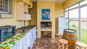 A kitchen with a microwave, stove, and bar stools. There is a painting of a dolphin on the wall and a wooden barrel. - Tuscany On Sea (Great Brak River)