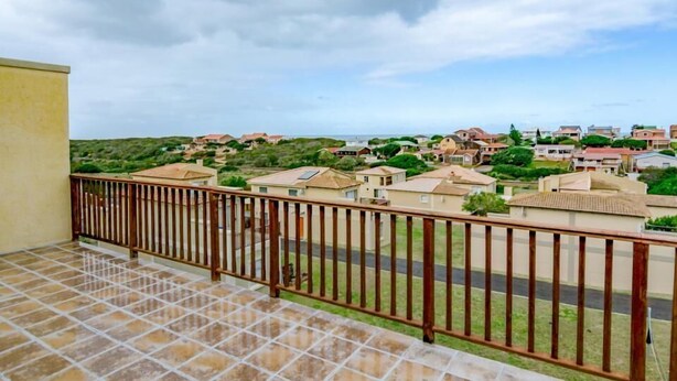 A balcony with a tiled floor and a metal railing overlooking a residential area with houses and greenery. - Tuscany On Sea (Great Brak River)