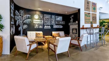 Ein moderner Lounge-Bereich mit weißen Ledersofas, Holz-Couchtischen und einer Wand in Schwarz mit Kaffeekunst.