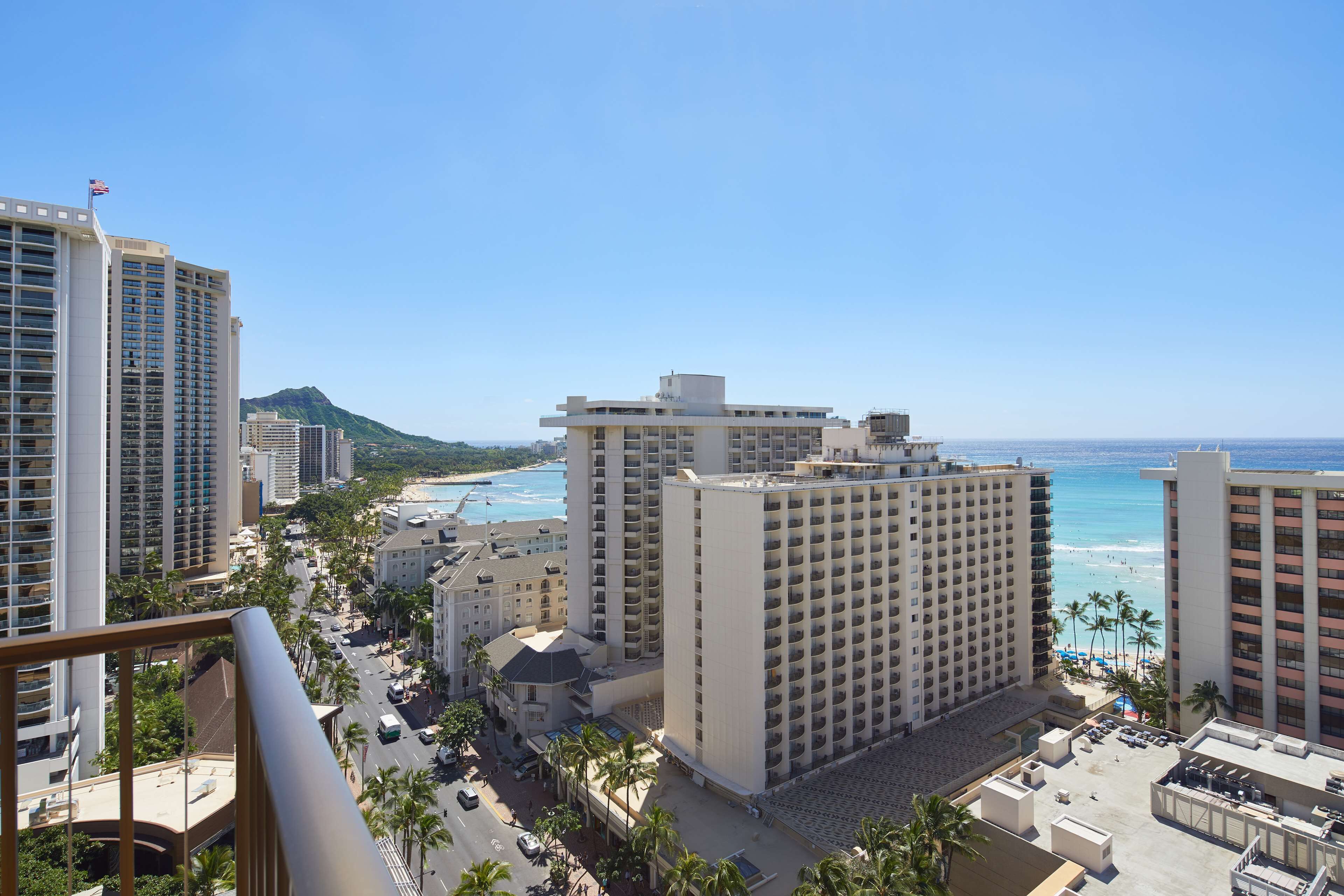 A high-rise hotel with multiple floors, a beach view, and a mountain in the background.