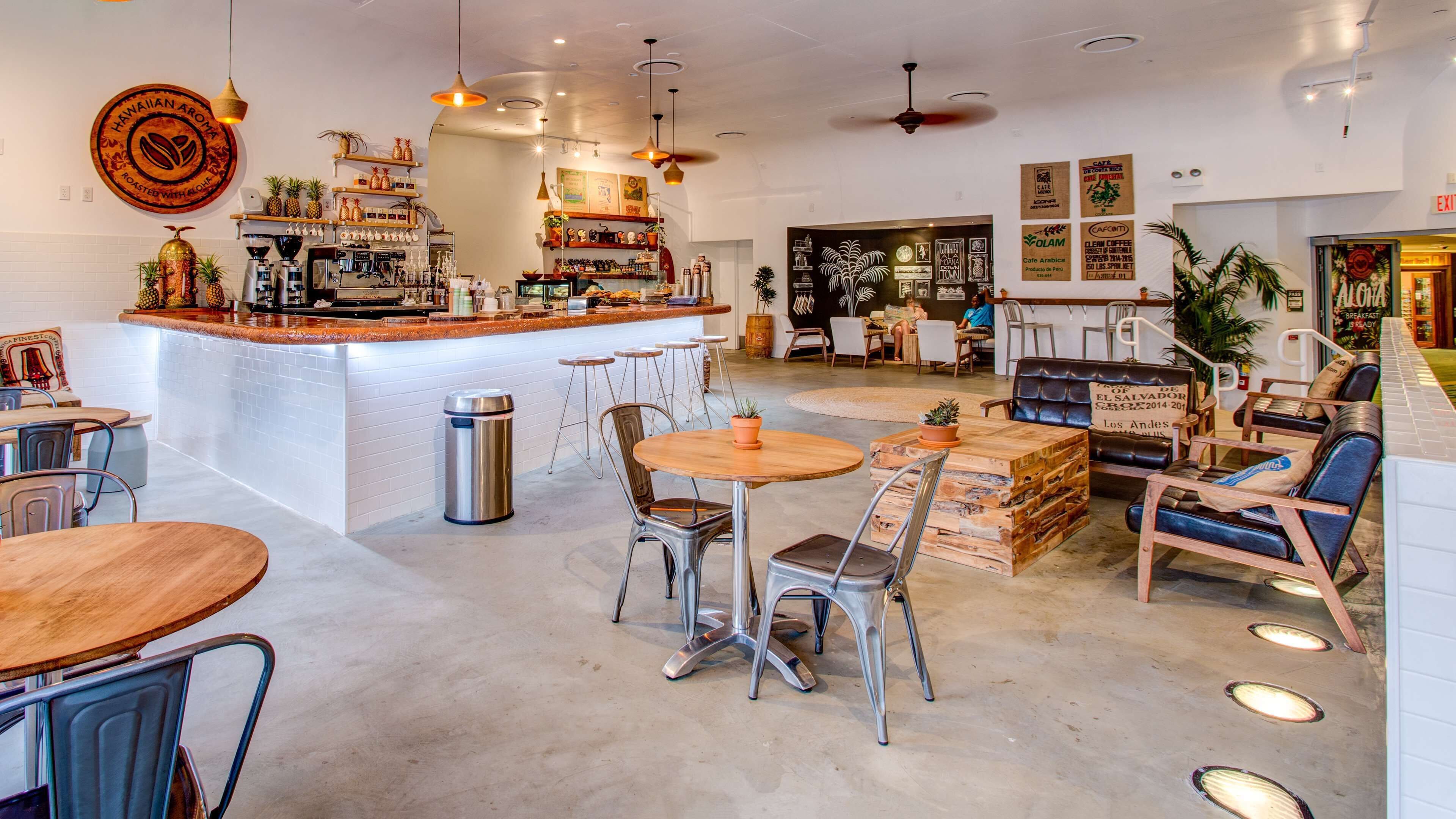 A café with a bar area, seating with tables and chairs, and a counter with various items.