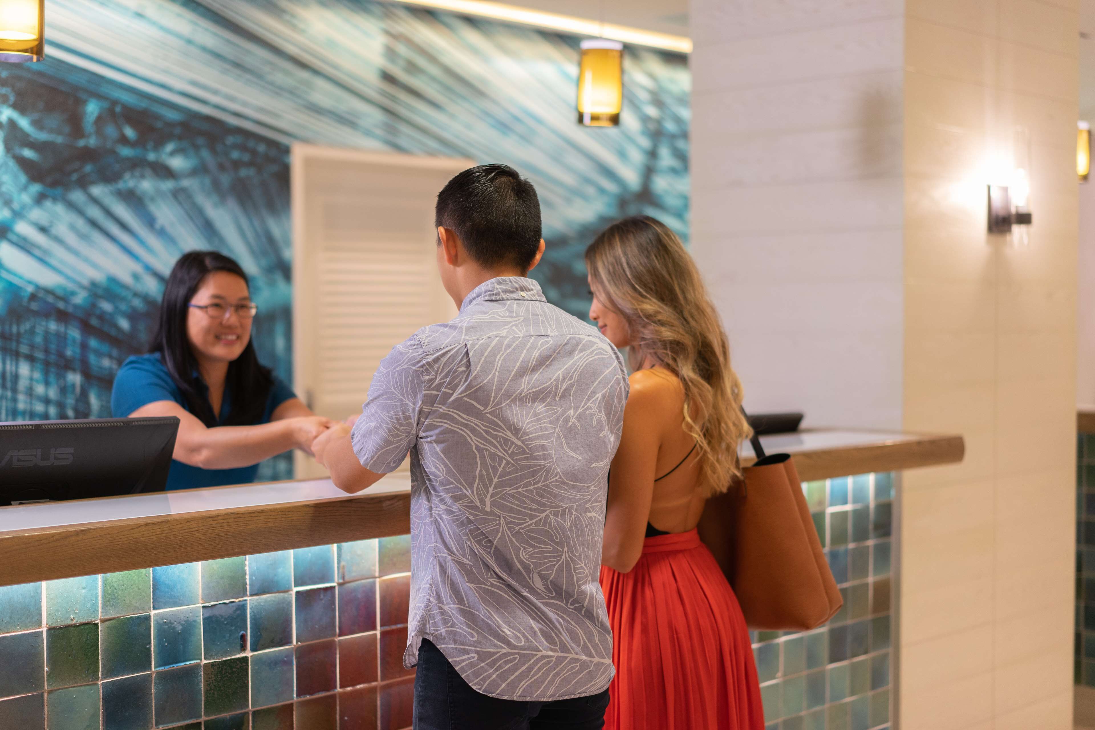 A reception area with a modern design, including a tiled wall and a reception desk.