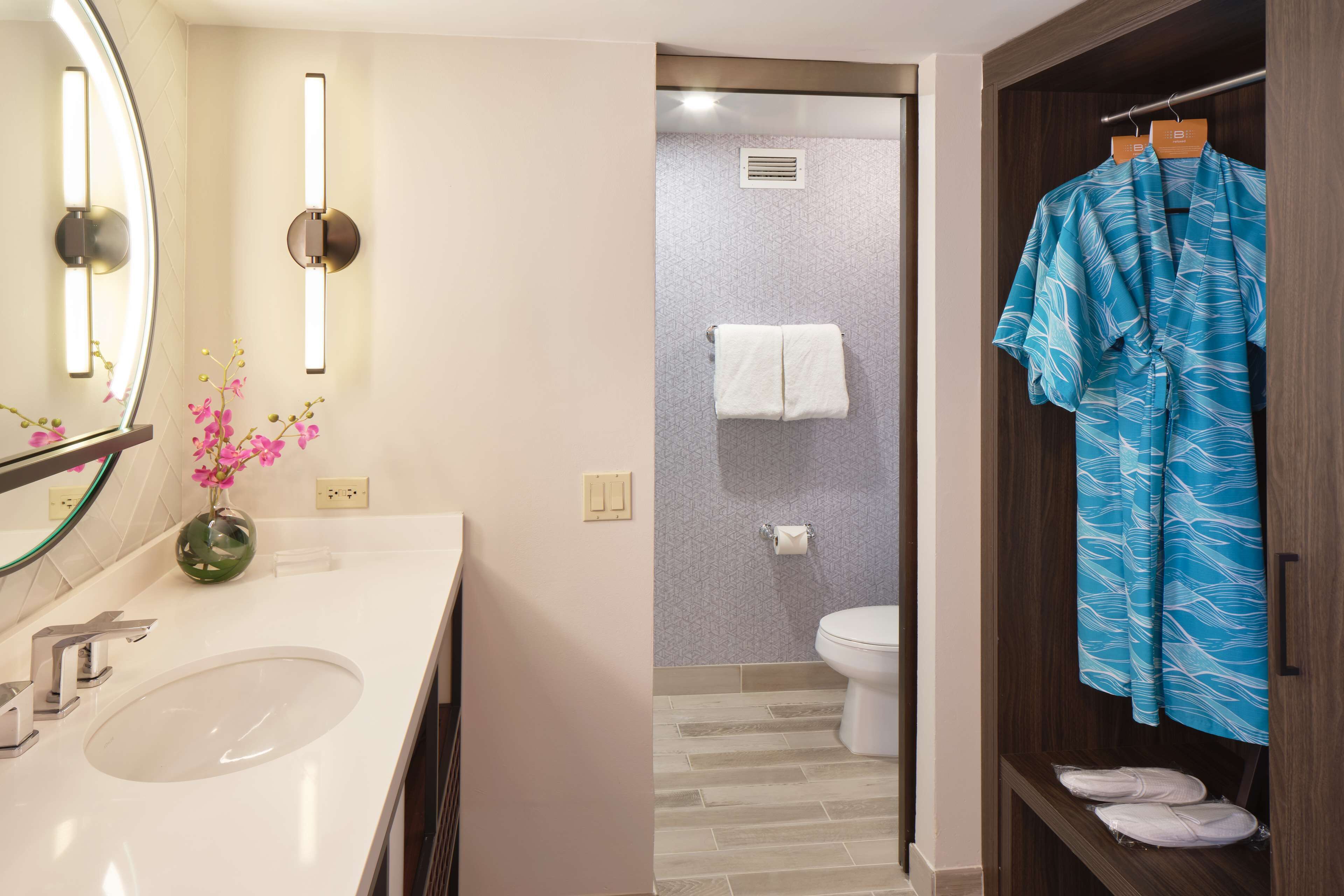 Un baño moderno con un espejo grande, un lavabo y un perchero para toallas.