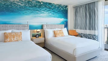 A hotel room with two beds, a city view, and a large ocean mural on the wall.