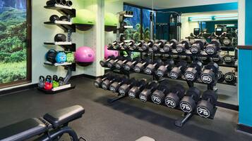 Un gimnasio con equipo de levantamiento de pesas, incluyendo mancuernas y balones kettlebell.