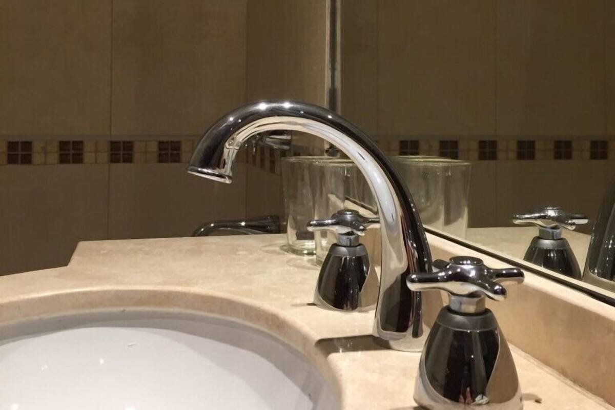 A bathroom with a sink, a mirror, and a tiled wall.