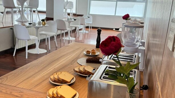 Une table en bois dressée pour le petit-déjeuner, avec un grille-pain, du pain et une rose.