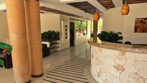 A hotel lobby with a reception desk, a stone wall, and a striped floor. - Condo Sabia Apartments by CSR (Playa del Carmen)