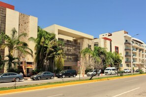 A modern hotel with a stone facade, palm trees, and a clear blue sky. - Condo Sabia Apartments by CSR (Playa del Carmen)