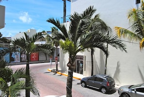 A street view with palm trees, parked cars, and a building with a sign that reads "Atelieria". - Apartment Luna Antigua 2 BR 1 Bth (Playa del Carmen)