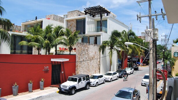 A modern building with a stone facade, a red wall, and a sign indicating it is a condominium. - Apartment Luna Antigua 2 BR 1 Bth (Playa del Carmen)