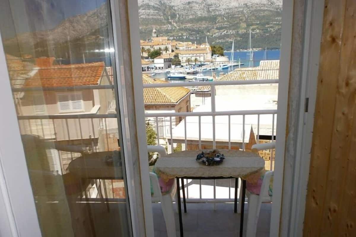 Un balcón con una mesa y sillas, con vista a una marina llena de barcos y edificios.