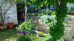 A garden with hanging planters, a stone wall, and various plants. - Apartments Neno (Korcula)