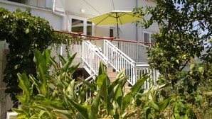 A staircase with white railings leading to a balcony with a yellow umbrella. - Apartments Neno (Korcula)