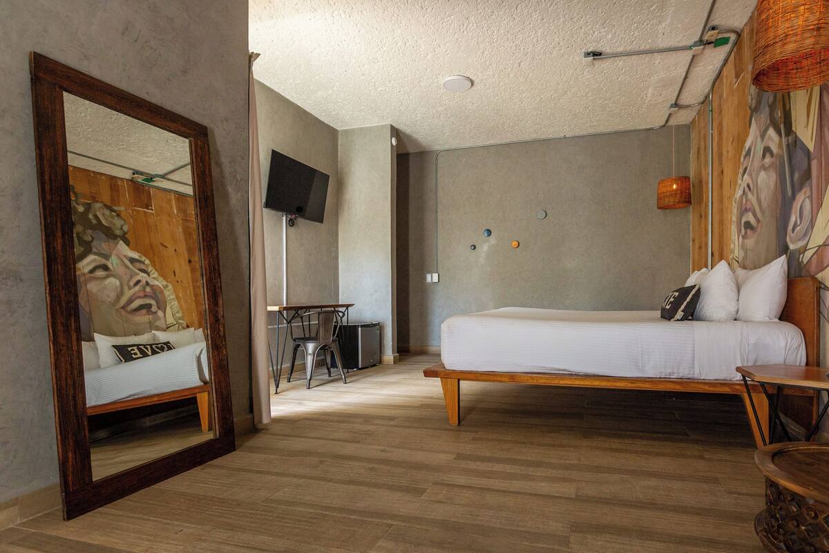 Ein Schlafzimmer mit einem Bett, einem Schreibtisch, einem Stuhl, einem Fernseher und einem Spiegel.