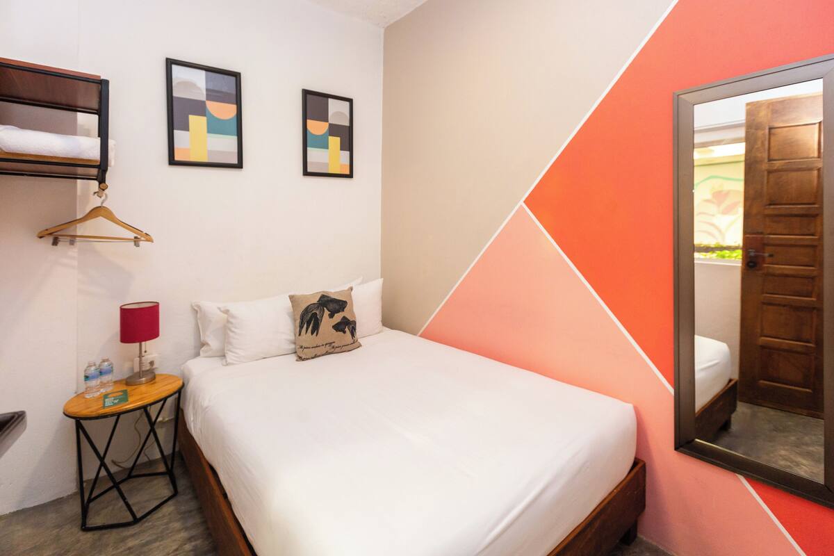 Ein Hotelzimmer mit einem Bett, einem Nachttisch mit Lampe, einem Holzanzhänger und zwei gerahmten Bildern an der Wand.
