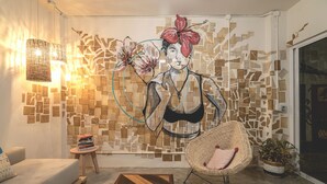 Una sala de estar moderna con un original cuadro de pared, una silla de mimbre, una pequeña mesa redonda y un sofá.