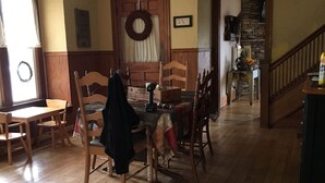 Ein Esszimmer mit Holzboden, einer Chandelierleuchtre und einer Treppe, die zu einer anderen Ebene führt.