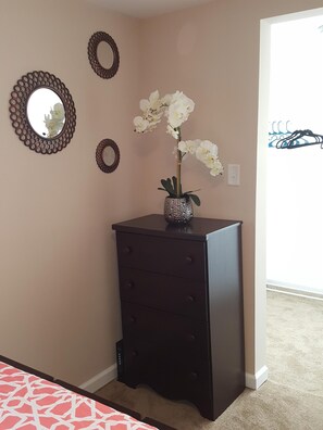 A room with a dark wooden dresser, a vase with white flowers, and three decorative mirrors on the wall.