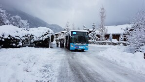 Um ônibus azul com a inscrição 'SKI BUS' em uma estrada coberta de neve.