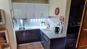 Uma cozinha compacta com pia, chaleira e geladeira.