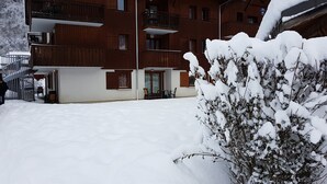 Um pátio coberto de neve com um edifício de madeira, com varandas e escadaria.