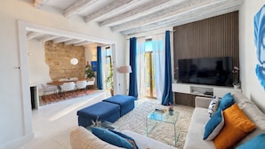 Ein modernes Wohnzimmer mit Steinwand, Essbereich und Fernseher an einer Holzwand.