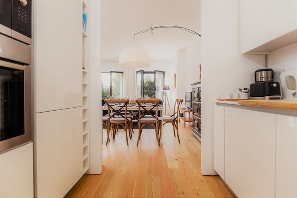 A modern kitchen with white cabinetry, a dining table with chairs, and a large window providing natural light.