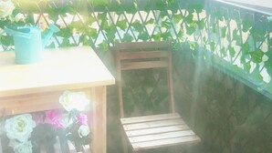 A wooden chair and a table with a blue watering can and flowers. - King Deluxe Apartments (Melbourne)