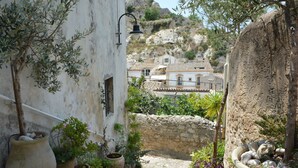 A narrow stone staircase leading to a courtyard with potted plants and a view of traditional buildings in the background.