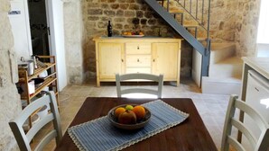 A rustic kitchen with a stone wall, wooden cabinets, and a staircase.