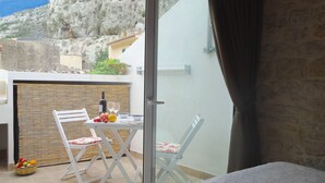 A balcony with a table set for two, a chair, and a basket of fruit.
