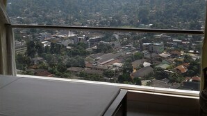 Una habitación con cama y un amplio ventanal con vistas a la ciudad y colinas.
